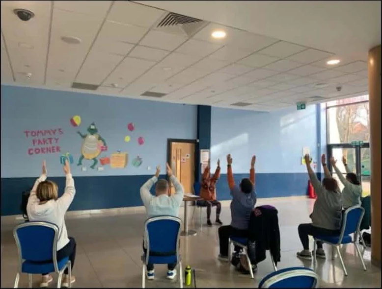 A chair-based exercise class in a community hall in Swansea