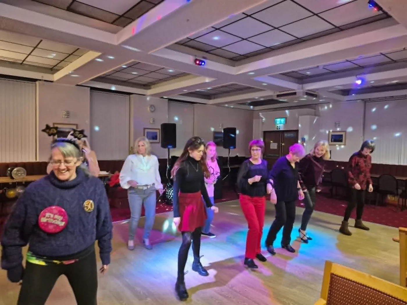 A group taking part in a line dance session together in a community venue