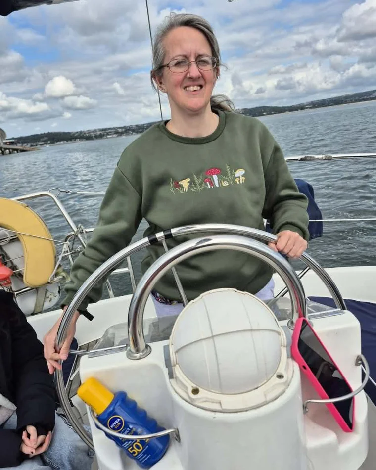 Anne smiling at the helm of a sailing boat