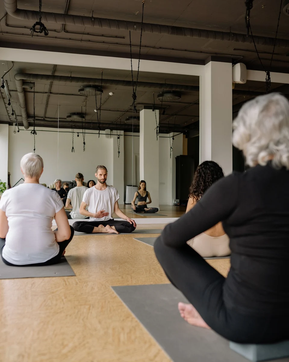 A mixed-age group sitting and practising gentle seated yoga in a bright, calm studio