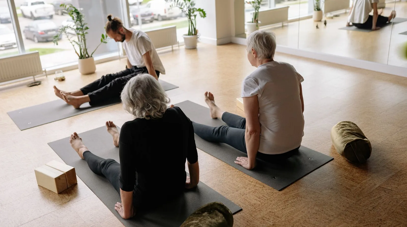 A friendly, inclusive gentle exercise class — older adults stretching in a bright, calm studio