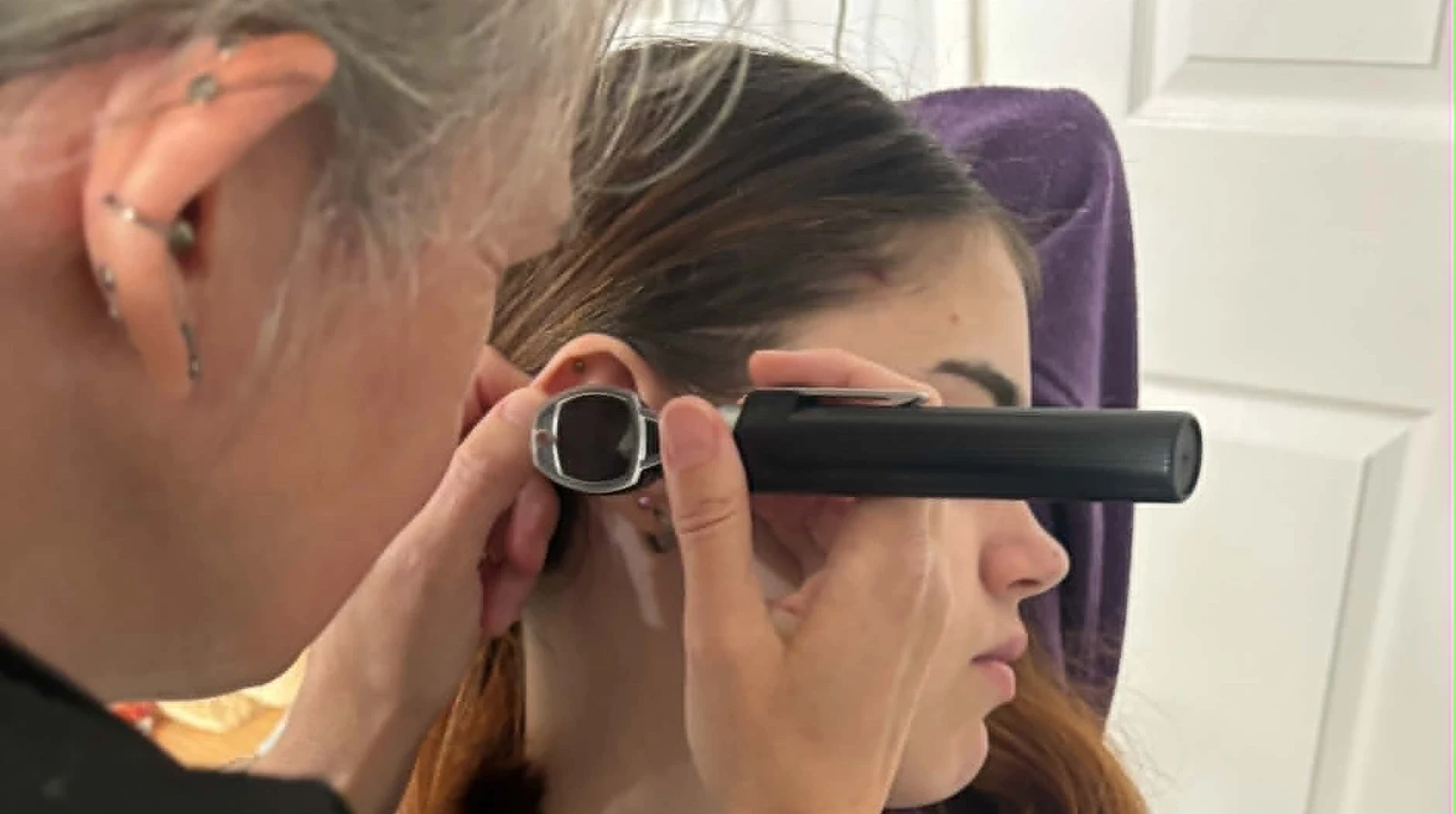 Anne examining a client's ear with an otoscope during an ear-care appointment