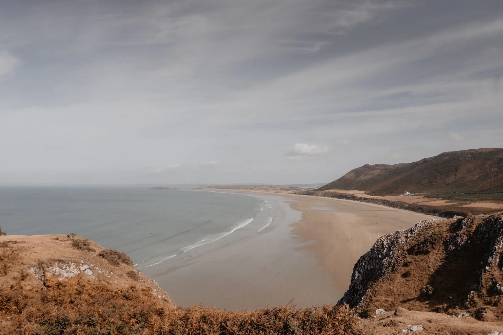 Rhossili Bay on the Gower, Swansea — the sweeping sandy bay and cliffs under a soft sky