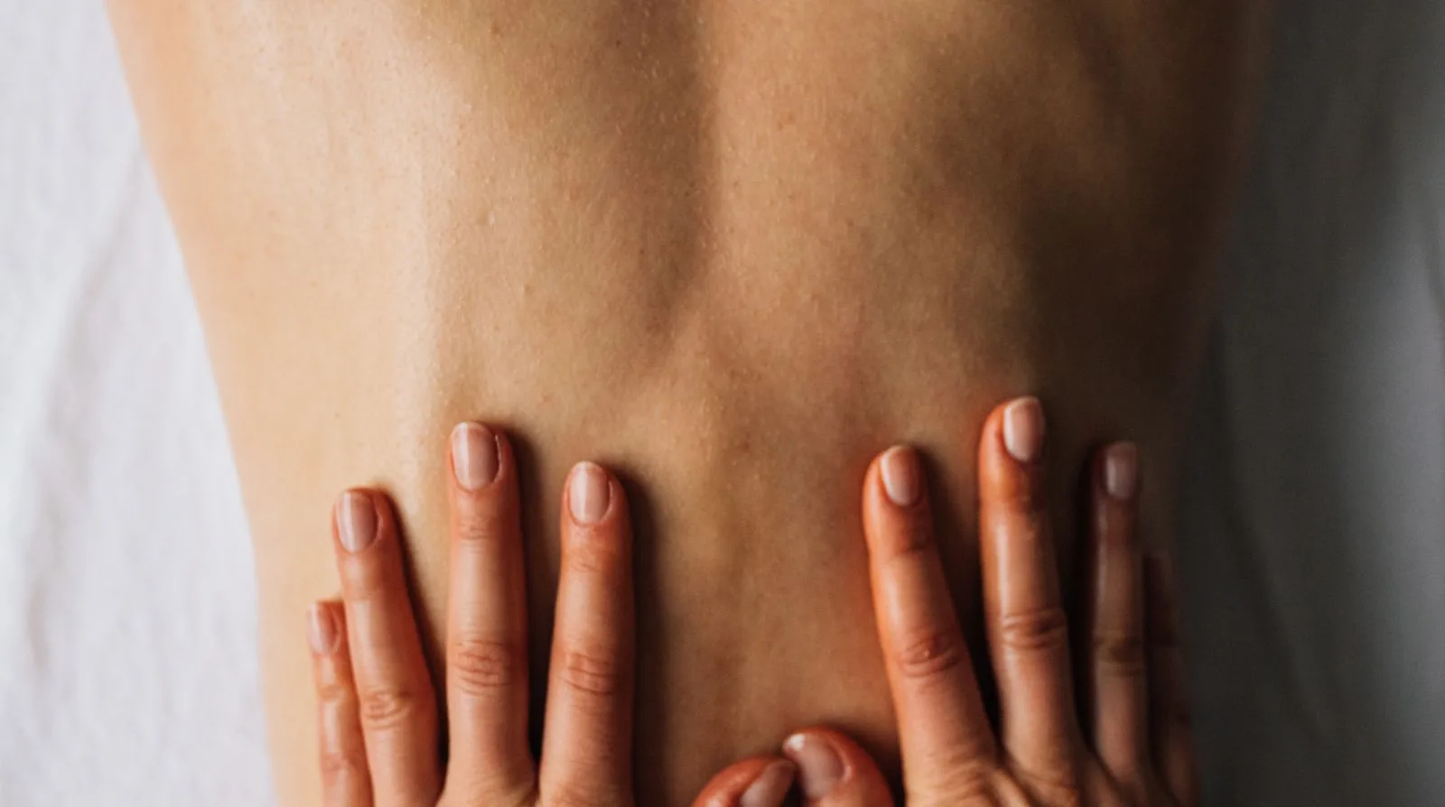 A professional back massage — a therapist's hands working gently on a client's back